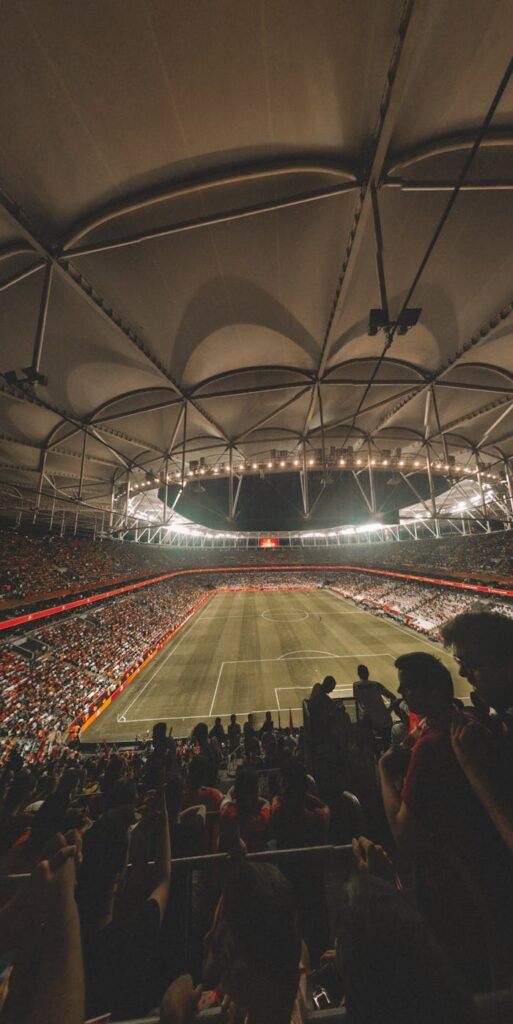 Exciting soccer game at night in a large modern stadium with a cheering crowd.